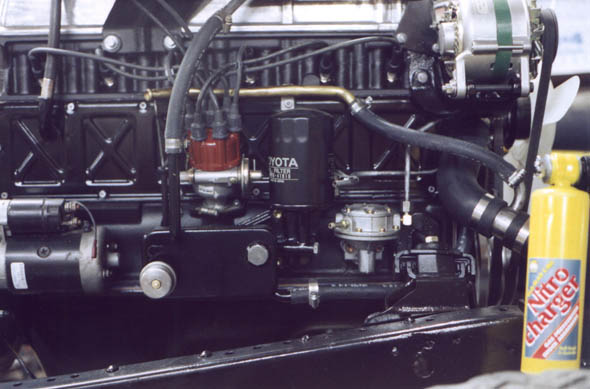 Side view showing starter, oil cooler, distributor, fuel pump, alternator, hoses and engine mount.